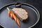 Minimalistic gourmet meatloaf slice with sliced carrot and ketchup on a modern design plate