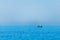Minimalistic image of the sea with a fishing boat. Blue sea water and clear sky