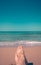 Minimalistic photo of woman`s feet on the beach overlooking the sea.