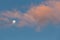 Minimalistic skyscape - moon, sky and clouds glowing in orange sunset light.