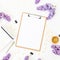 Minimalistic workspace desk with clipboard, notebook, lilac and accessories on white background. Flat lay, top view. Beauty or wed