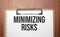 minimizing risks text on white paper on the wood table
