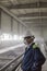 Mining engineer in white helmet and respirator inspects dusty dirty workshop