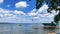 Minnesota lake scene with pontoon, dock, flag, tree, clouds and blue sky.