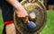 Minority man in traditional dress knocking a copper gong