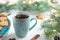 Mint cup of tea with heart, gingerbread next to branches of a Christmas tree with ight bulbs on white wooden background