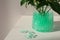 Mint filler and green branches in glass vase on white table, space for text. Water beads