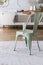 Mint green chair on grey carpet at table in rustic dining room interior with lamp and wall with molding. Real photo