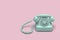 Mint green rotary telephone on pink background