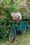 A mint retro Bicycle with a straw hat on the handlebars and peonies in a basket, stands in the middle of a beautiful garden