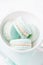 Mint or tiffany color macaron or macaroon dessert with vanilla cream in white cup. Copy space