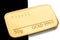 Minted gold bar weighing 50 grams on a black and white background.