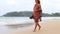 MIRISSA, SRI LANKA - MARCH 2014: Woman in sarong around her shoulders walking down the beach. This small sandy tropical beach boas