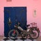 Mirleft, Morocco - vintage Motobecane motorcycle leans on a blue Moroccan double door with symbols. Quirky postcard.