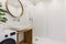 Mirror above washbasin in white bathroom interior with shower an