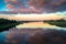 Mirror glossy surface of the Volga river reflects dramatic sunset sky. City of Tver, Russia.