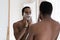 Mirror reflection smiling African American man applying shaving foam