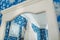 Mirror`s reflection of cream bridal dress which hangs on the cornice on a background the blue floral pattern wall.