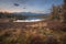 Mirror Surface Lake Autumn Landscape With Mountain Range On Background With Light Pink Sky