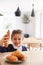 Mischievous Girl Wearing School Uniform Taking Croissant From Kitchen Counter