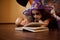 Mischievous little girl with Halloween make-up dressed as witch, sorceress in wizard& x27;s hat reading a book of