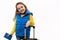 Mischievous Little girl in yellow sweater and blue down jacket poses with boarding pass and suitcase over white backdrop