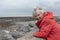 Mischievous senior woman laughing on a rocky beach