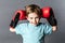 Mischievous young boy with freckles holding his boxing gloves up