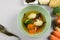 Miso soup with vegetables, cooked in dish and fresh around it, carrot, onion, seaweed, broccoli, cauliflower on light background.
