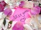 Miss you message on pink sticky note with dry rose and orchid flower petals and jewelry ring and chain on wooden background