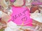 Miss you message on pink sticky note with dry rose and orchid flower petals and silver jewelry ring and chain on wooden background