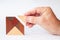 The missing building block is inserted into a tangram made of fine wood by a senior`s hand