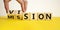Mission vision symbol. Businessman hand turns wooden cubes and changes the word `mission` to `vision`. Beautiful yellow table,