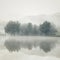 Mist on a lake at dawn with trees and mountains reflected in the