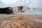 The mist over the geyser and the bizarre patterns on the bottom of the pool in the Yellowstone national park