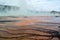 The mist over the geyser and the bizarre patterns on the bottom of the pool in the Yellowstone national park