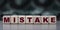 MISTAKE - word on wooden cubes on blurred camouflage background