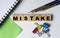 MISTAKE - word on wooden cubes with stationery clips, pencils, notebook