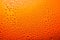 misted glass of beer close up an orange bright background