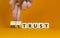 Mistrust or trust symbol. Businessman turns wooden cubes, changes words `mistrust` to `trust`. Beautiful orange table, orange