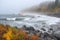 misty autumn shoreline with crashing waves and fishing boats