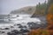 misty autumn shoreline with crashing waves and fishing boats