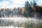 Misty lake with forested shores in autumn