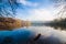 Misty late autumn morning, sleepy natural lake enjoys first sun rays getting through tree branches, attractive tourist sightseeing