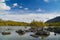 Misty morning on a small mountain lake with a scattering of boulders, reflecting dense clouds, surrounded by autumn