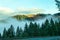 Misty Mountains - View from highway of distant mountaintop in the sunlight above the fog settled in the valley of Northern