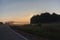 Misty road through green fields with road signs and low visibility