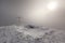 Misty snow-covered mountain with cross and sunlight