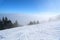 Misty snow slope with trees