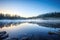 misty sunrise mirrored on the surface of a placid lake